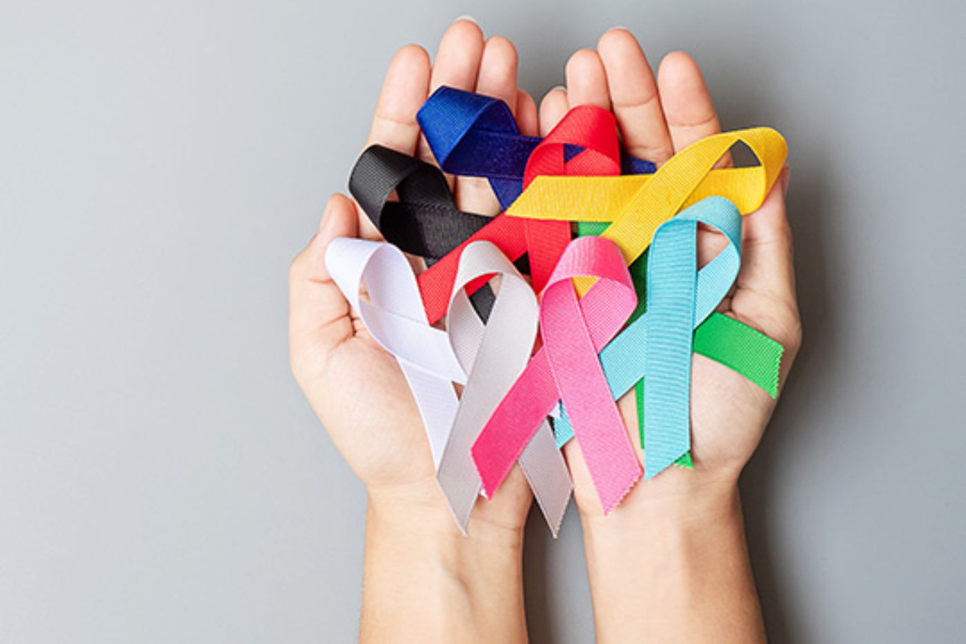 Manos cogiendo unos lazos del día mundial contra el cáncer