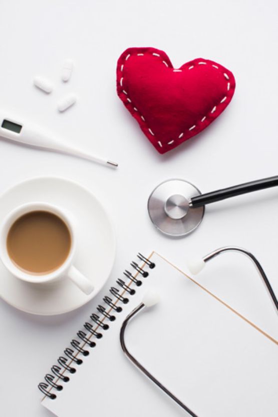 Taza de café con corazón de juguete rojo y accesorios médicos sobre escritorio