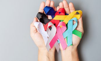 Manos cogiendo unos lazos del día mundial contra el cáncer