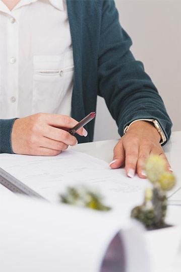 Mujer firmando un papel en la mesa de una despacho