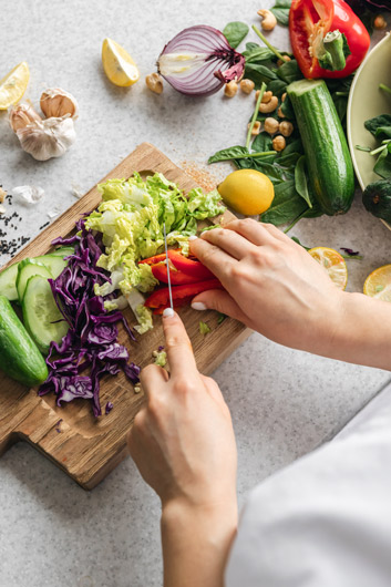 Persona preparant un menjar amb ingredients frescos, un exemple pràctic d'hàbits d'alimentació sostenible i saludable.