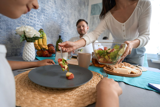Mujer recibiendo ensalada en un plato en la mesa