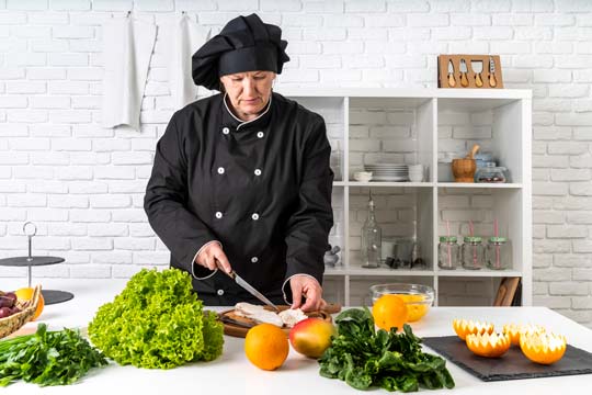 Chef cortando carne en la cocina