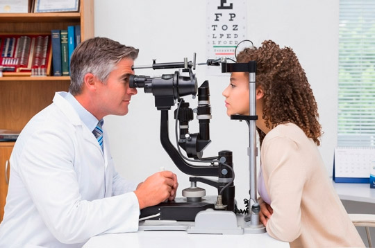 Optometrista realizando un examen ocular con lámpara de hendidura a una paciente