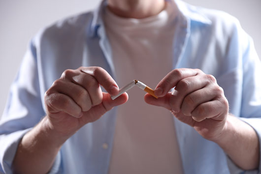 Persona rompiendo un cigarrillo, simbolizando la prevención de adicciones