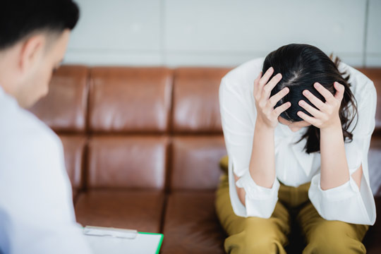 Mujer con depresión cogiendose la cabeza en un consultorio de un terapeuta