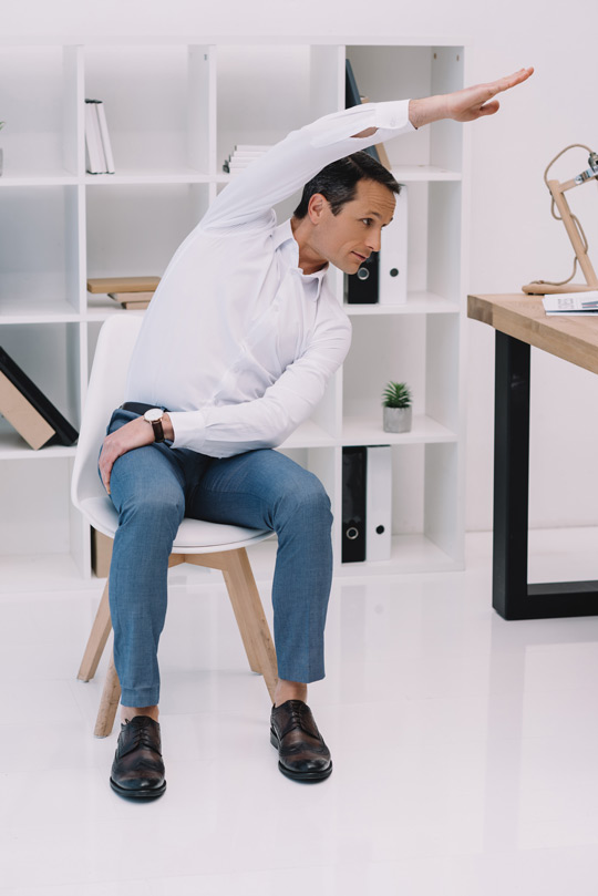 Persona haciendo una curva lateral en la silla de la oficina