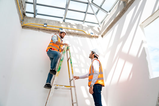 Persona observando a otra persona en una plataforma alta de acero en el sitio de construcción