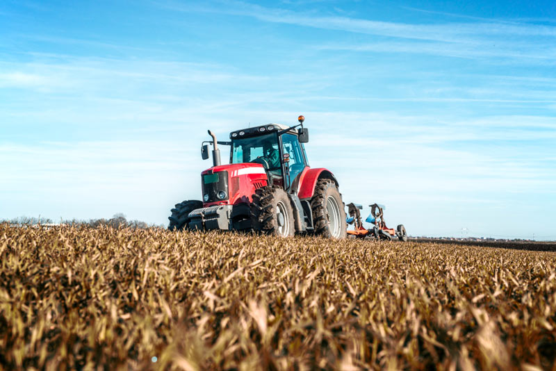 Tractor trabajando en un campo de cultivo, representando el sector agrario.